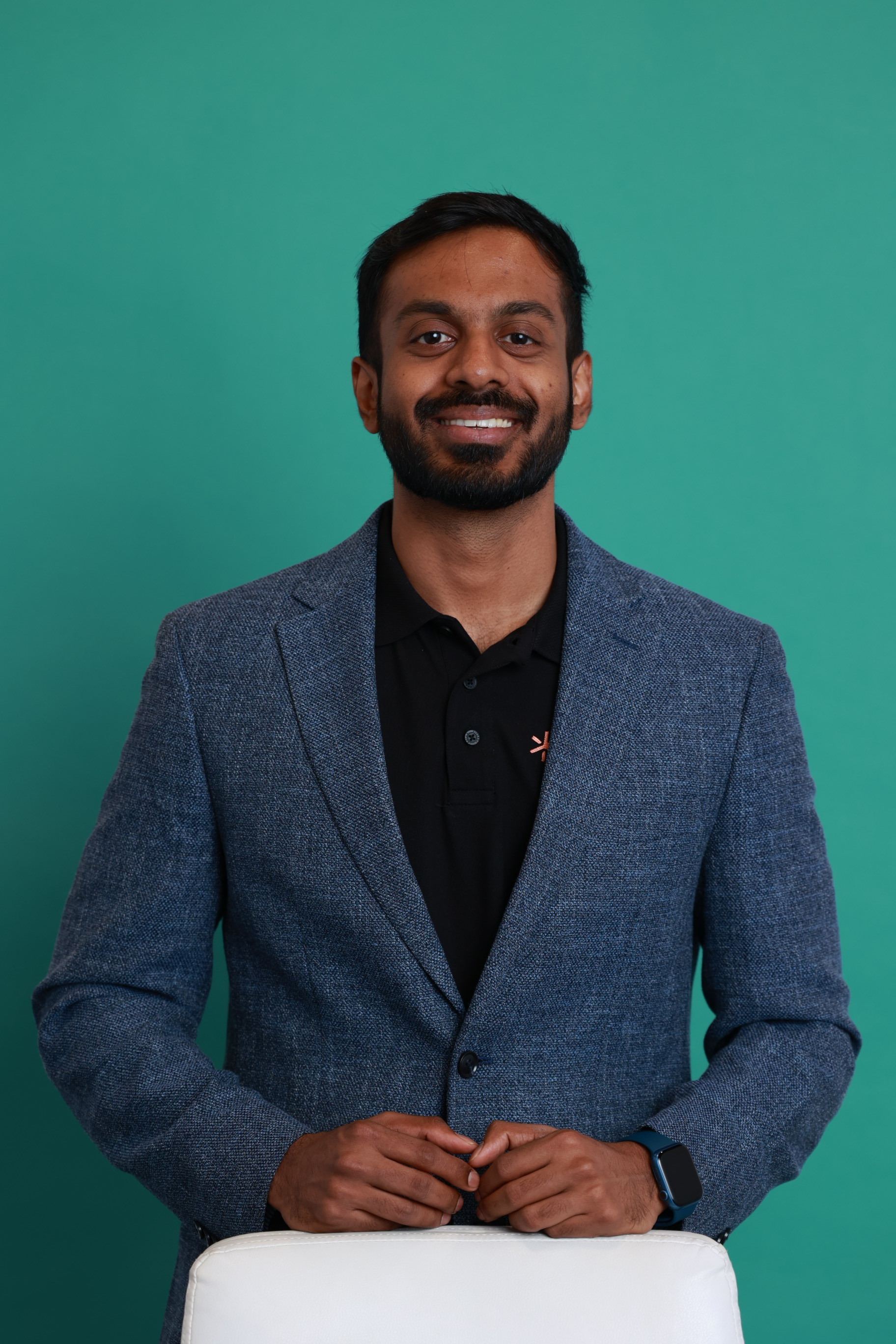 Nithin Chandra smiling in a blue blazer against a teal background