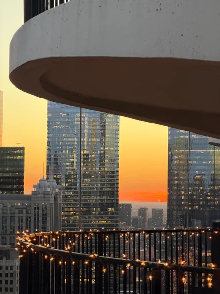 A curved balcony frames city towers and warm evening light.