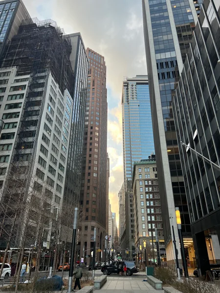 Tall city buildings converge around a narrow patch of pale sky.